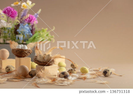 Easter decorative composition with quail eggs, feathers, wooden figures, and spring flowers on a beige background. 136731318