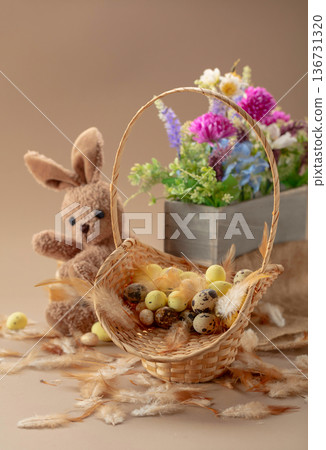 Easter decorative composition with quail eggs, feathers, spring flowers, and toy bunny on a beige background. Easter decorative composition with quail eggs, feathers, spring flowers, and toy bunny on a beige background. 136731320