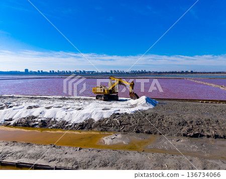 Heavy machinery works on salt flat near city under clear blue sky during day Heavy machinery works on salt flat near city under clear blue sky during day 136734066