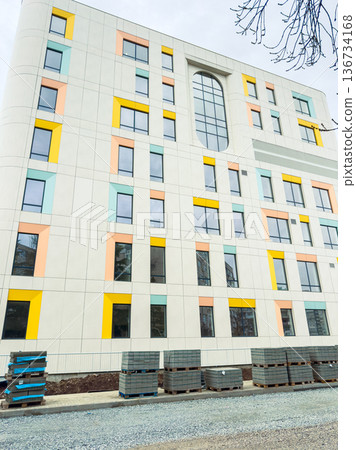 New building under construction with colorful panels and stacks of materials on the ground near the site in the city New building under construction with colorful panels and stacks of materials on the ground near the site in the city 136734168