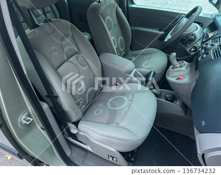 View of front seats in a small car with patterned upholstery and simple interior design taken in a parking area during daylight View of front seats in a small car with patterned upholstery and simple interior design taken in a parking area during daylight 136734232