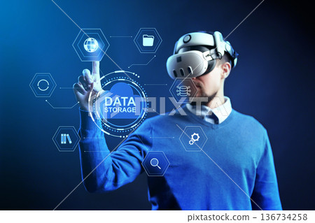 Person uses virtual reality headset to interact with data storage concepts in a dark space Person uses virtual reality headset to interact with data storage concepts in a dark space 136734258