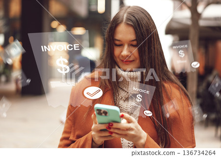 Woman checks banking invoice payment on her phone in a busy city street at noon Woman checks banking invoice payment on her phone in a busy city street at noon 136734264