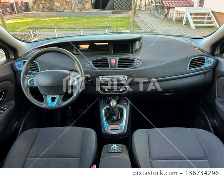 Car interior shows steering wheel and dashboard with controls in a clean vehicle setting during daytime Car interior shows steering wheel and dashboard with controls in a clean vehicle setting during daytime 136734296