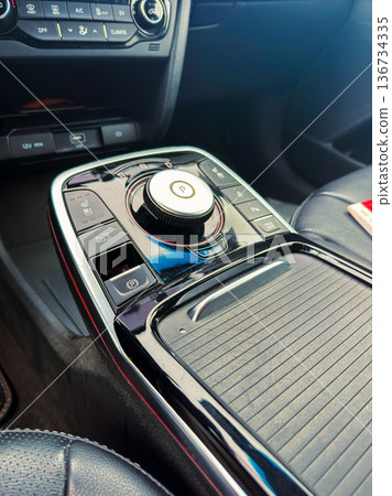 Control panel in a modern car with various buttons and a gear shifter located near the center console 136734335