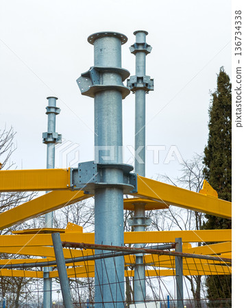 Construction site with metal frameworks and yellow supports under a cloudy sky in an urban area during daytime 136734338