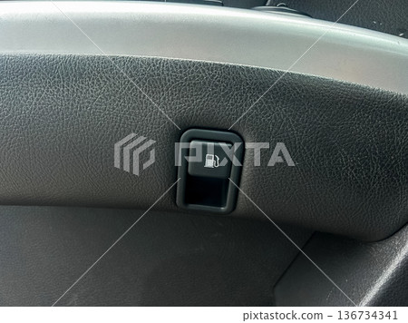 Fuel door release button is located inside a car dashboard near the steering wheel for vehicle refueling access in the driver's compartment Fuel door release button is located inside a car dashboard near the steering wheel for vehicle refueling access in the driver's compartment 136734341