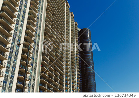 Modern buildings stand tall against blue sky in urban area showcasing city landscape during daytime Modern buildings stand tall against blue sky in urban area showcasing city landscape during daytime 136734349