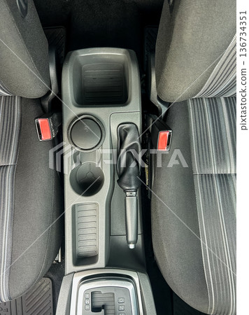 Central console and gear shift of a car showing storage areas and seating arrangement for two front seats 136734351