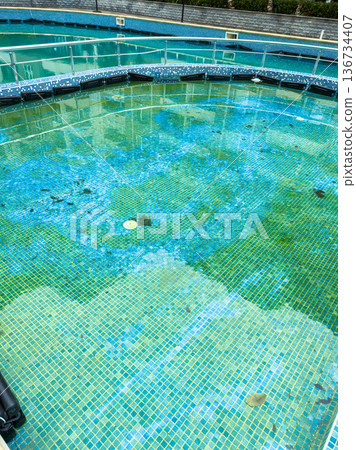 Bright blue water in an empty swimming pool under a cloudy sky during the day with visible tiles on the bottom and edges of the pool Bright blue water in an empty swimming pool under a cloudy sky during the day with visible tiles on the bottom and edges of the pool 136734407