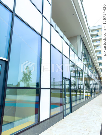 Modern building with large glass windows in a city setting during daytime showcasing colorful design 136734420