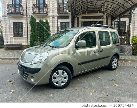 Car parked in front of a large building during daytime with trees and a covered entrance Car parked in front of a large building during daytime with trees and a covered entrance 136734424