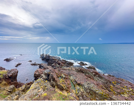 Sky over rocky coastline and ocean with waves on a cloudy day near the shore in a seaside area 136734442