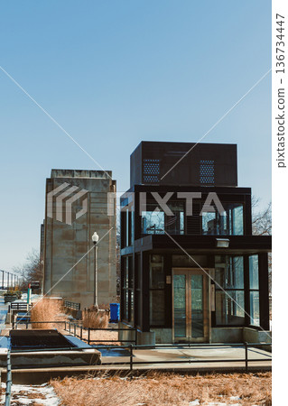 Modern architecture beside a large concrete structure during a clear day in an open space Modern architecture beside a large concrete structure during a clear day in an open space 136734447