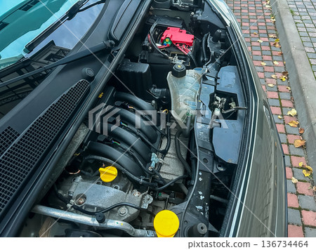 Car engine view showing various components and parts in a close-up shot during a maintenance check on a vehicle on a city street Car engine view showing various components and parts in a close-up shot during a maintenance check on a vehicle on a city street 136734464