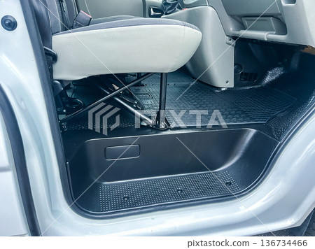 Detailed view of car interior showing seat, floor mat, and footwell area in a vehicle parked in a garage during daytime Detailed view of car interior showing seat, floor mat, and footwell area in a vehicle parked in a garage during daytime 136734466