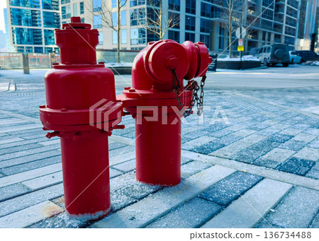 Fire hydrants stand on a city street in winter near tall buildings with a clear sky and no people in view Fire hydrants stand on a city street in winter near tall buildings with a clear sky and no people in view 136734488