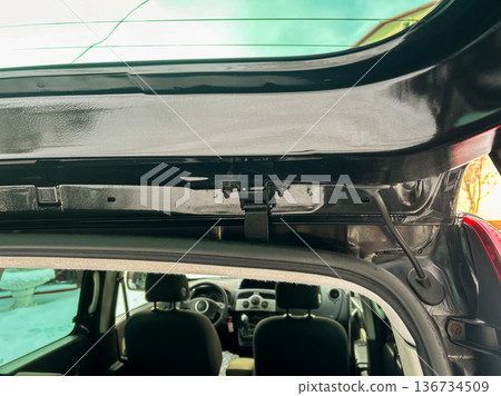 View of car interior showing the hatch area and parts of the rear seat during the day near a house in a suburban area 136734509