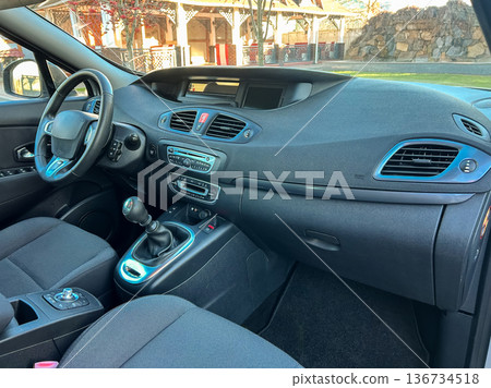 Interior view of a car showing the dashboard, steering wheel, and front seats in a parking area during daylight Interior view of a car showing the dashboard, steering wheel, and front seats in a parking area during daylight 136734518
