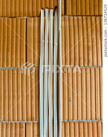 Wiring installation on a brick wall during construction process at a building site in mid-afternoon 136734529