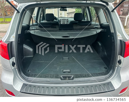 Car trunk is open showing a spacious interior with a cover and no items visible, parked in a residential area during the day Car trunk is open showing a spacious interior with a cover and no items visible, parked in a residential area during the day 136734565