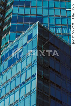 Bright sunlight reflects on glass building in city during afternoon hours while showcasing modern architecture and urban lifestyle Bright sunlight reflects on glass building in city during afternoon hours while showcasing modern architecture and urban lifestyle 136734577