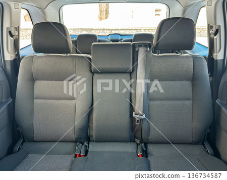 Empty back seat area of a car showing space for passengers and seat belts, located in a parking area during daylight hours Empty back seat area of a car showing space for passengers and seat belts, located in a parking area during daylight hours 136734587