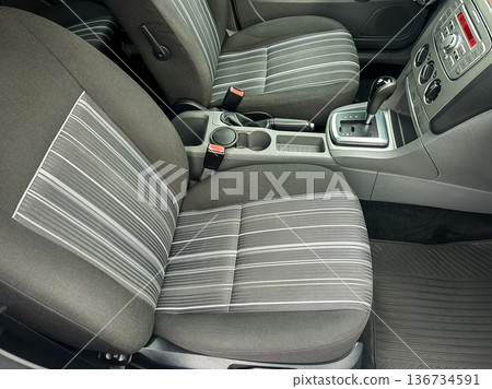 Interior view of a car showing front seats and center console with gear shift and parking brake in clear daylight Interior view of a car showing front seats and center console with gear shift and parking brake in clear daylight 136734591