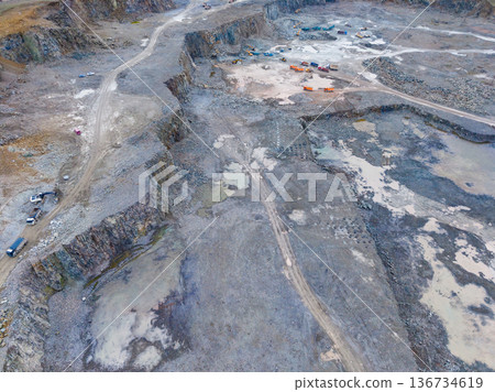 Large mining site shows heavy machinery and vehicles working on extraction and excavation activities in an open area during daytime 136734619