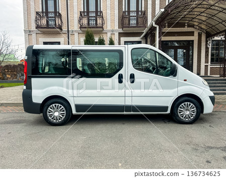 Large white van parked outside a building with brick walls and a canopy on a cloudy day near a driveway with no clear visible traffic Large white van parked outside a building with brick walls and a canopy on a cloudy day near a driveway with no clear visible traffic 136734625