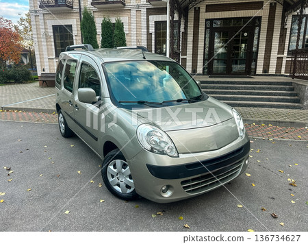 Silver compact car parked in front of a building with trees in a urban setting during daylight hours Silver compact car parked in front of a building with trees in a urban setting during daylight hours 136734627