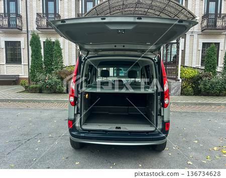 Back view of a van parked in front of a building with open trunk showing empty cargo space in the daylight Back view of a van parked in front of a building with open trunk showing empty cargo space in the daylight 136734628