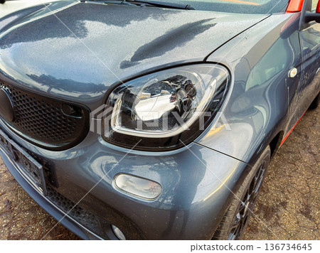 Smart car parked on street with wet pavement and cloudy sky in the background during a day in fall Smart car parked on street with wet pavement and cloudy sky in the background during a day in fall 136734645