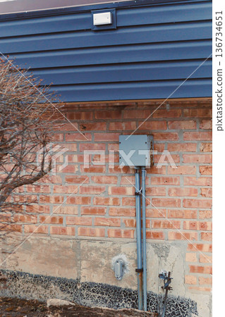 Close view of a brick wall with electrical box and pipes located on a building exterior at a construction site during the day Close view of a brick wall with electrical box and pipes located on a building exterior at a construction site during the day 136734651