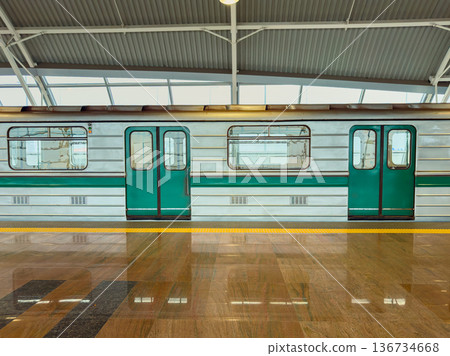 Green and silver subway train waits at a station platform during a busy day in the city Green and silver subway train waits at a station platform during a busy day in the city 136734668