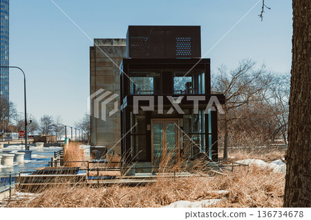 Modern building stands near lakeshore in Chicago with clear sky and surrounding greenery during daytime Modern building stands near lakeshore in Chicago with clear sky and surrounding greenery during daytime 136734678