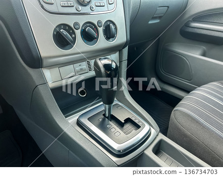 Detailed view of a car's gear shift and center console showing controls and layout during daylight in a parked vehicle Detailed view of a car's gear shift and center console showing controls and layout during daylight in a parked vehicle 136734703