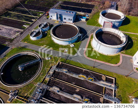 Water treatment plant shows various tanks and structures used for cleaning wastewater in a large facility located outdoors on a sunny day 136734706