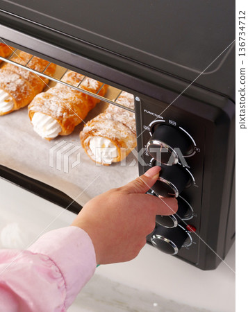 Baking dessert pastries in an oven with cream filling and powdered sugar at home Baking dessert pastries in an oven with cream filling and powdered sugar at home 136734712