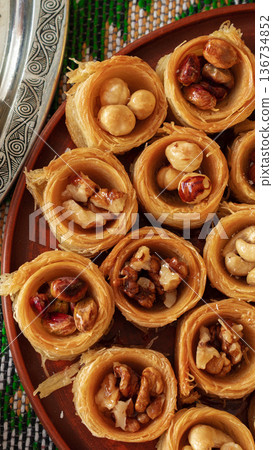 Baklava dessert with nuts served on a round plate in a bright kitchen setting 136734852