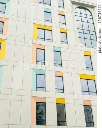 Modern building facade with colorful window frames in an urban setting during daytime 136734861