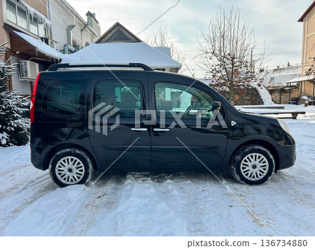 Black van parked on a snowy street near buildings and trees during a clear day in winter Black van parked on a snowy street near buildings and trees during a clear day in winter 136734880