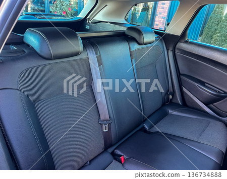 Car interior shows backseat space with black fabric and cushions while parked in a residential area during daylight Car interior shows backseat space with black fabric and cushions while parked in a residential area during daylight 136734888