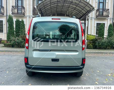 View of the rear of a silver van parked outside a building with architectural features and greenery on a clear day View of the rear of a silver van parked outside a building with architectural features and greenery on a clear day 136734916