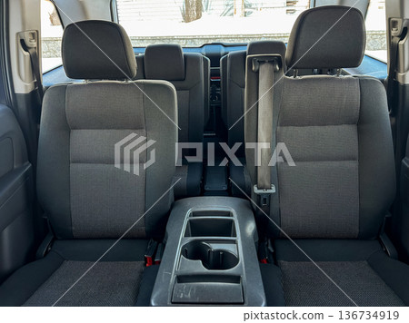 Interior view of a vehicle showing rear seats and center console in a parking area during daytime Interior view of a vehicle showing rear seats and center console in a parking area during daytime 136734919