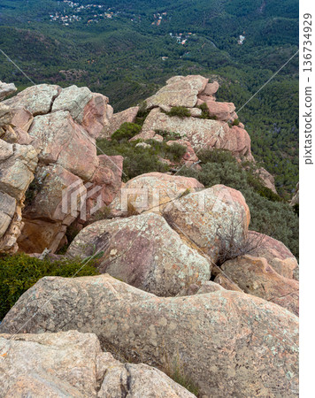 View from the top of the mountain showing rocky terrain and greenery below with a vast landscape in the distance during daylight hours View from the top of the mountain showing rocky terrain and greenery below with a vast landscape in the distance during daylight hours 136734929