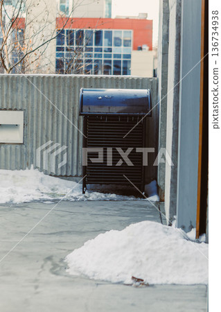 Snow covers the ground near a trash can in an urban setting during winter with buildings in the background Snow covers the ground near a trash can in an urban setting during winter with buildings in the background 136734938