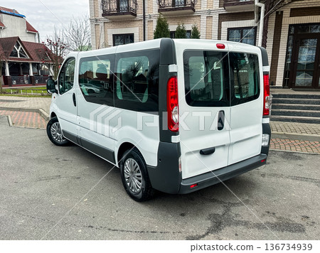 Van parked on a street near a building with balconies and a well-maintained outdoor area on a cloudy day Van parked on a street near a building with balconies and a well-maintained outdoor area on a cloudy day 136734939