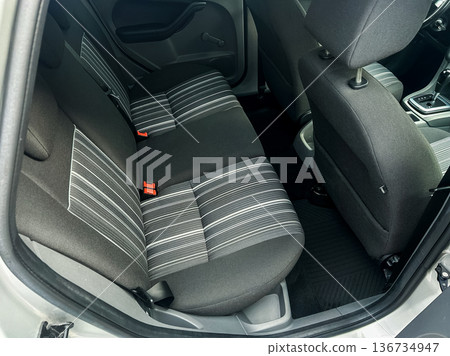 Rear seats of a car showing gray and black striped fabric along with seat belts and interior details in bright lighting Rear seats of a car showing gray and black striped fabric along with seat belts and interior details in bright lighting 136734947