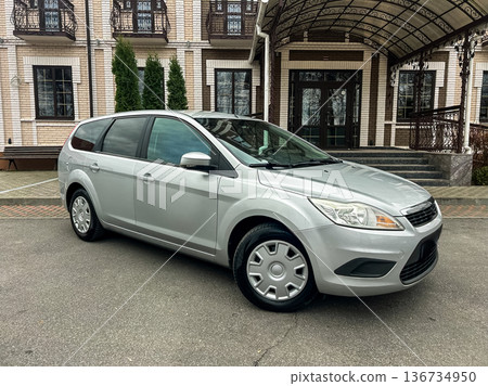Silver car parked in front of a building with a brick facade and large windows in a residential area on a cloudy day Silver car parked in front of a building with a brick facade and large windows in a residential area on a cloudy day 136734950